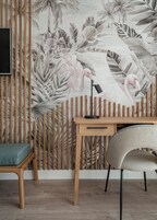 A room with a wooden desk, a chair, and a wall with a tropical mural.