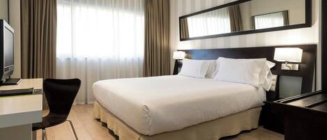 Una habitación de hotel con cama, escritorio, silla y un espejo grande.