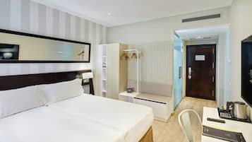 Une chambre d’hôtel comprenant un lit, un bureau avec une chaise, un miroir, une armoire et une porte.