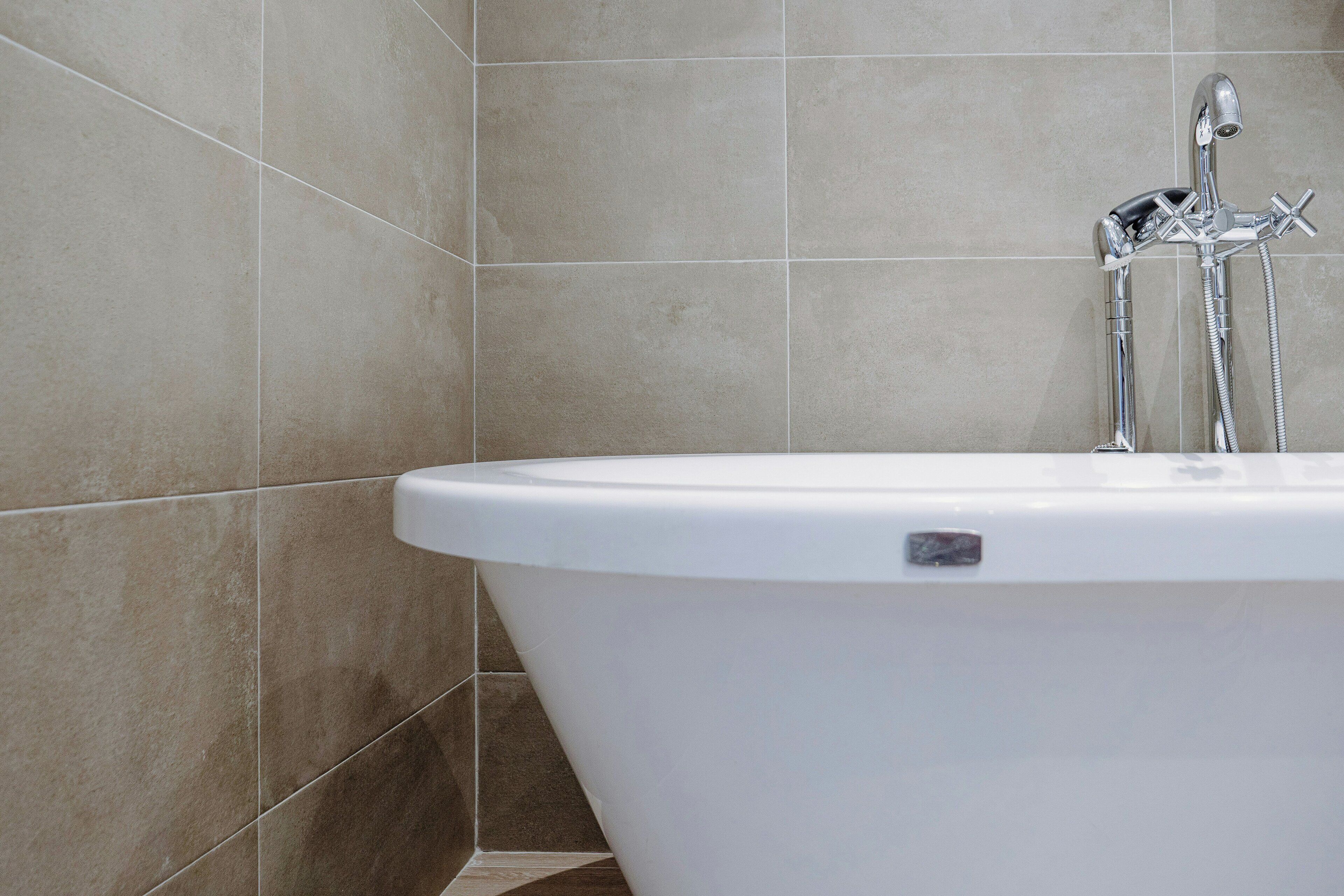 A modern bathroom with a freestanding bathtub, chrome fixtures, and tiled walls.