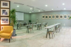 A conference room with tables and chairs, a potted plant, and framed pictures on the wall.