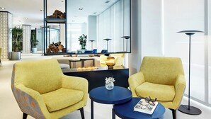 Un salon moderne avec deux fauteuils jaunes, une table basse ronde et un grand miroir.