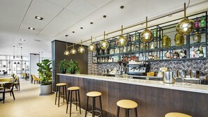 Un espace bar avec des tabourets, un comptoir et des étagères remplies de bouteilles.