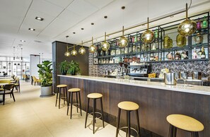 A bar area with stools, a counter, and shelves with bottles. - Sercotel Madrid Aeropuerto (Madrid)