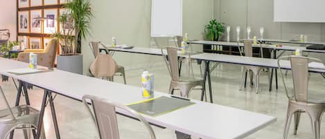 Un salón de conferencias con mesas, sillas, una pizarra y cuadros en la pared.