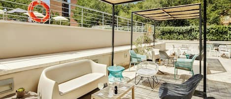 An outdoor patio with a sofa, chairs, a table, and umbrellas.