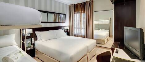 A hotel room with a bed, a desk with a computer, a TV, and a mirror.