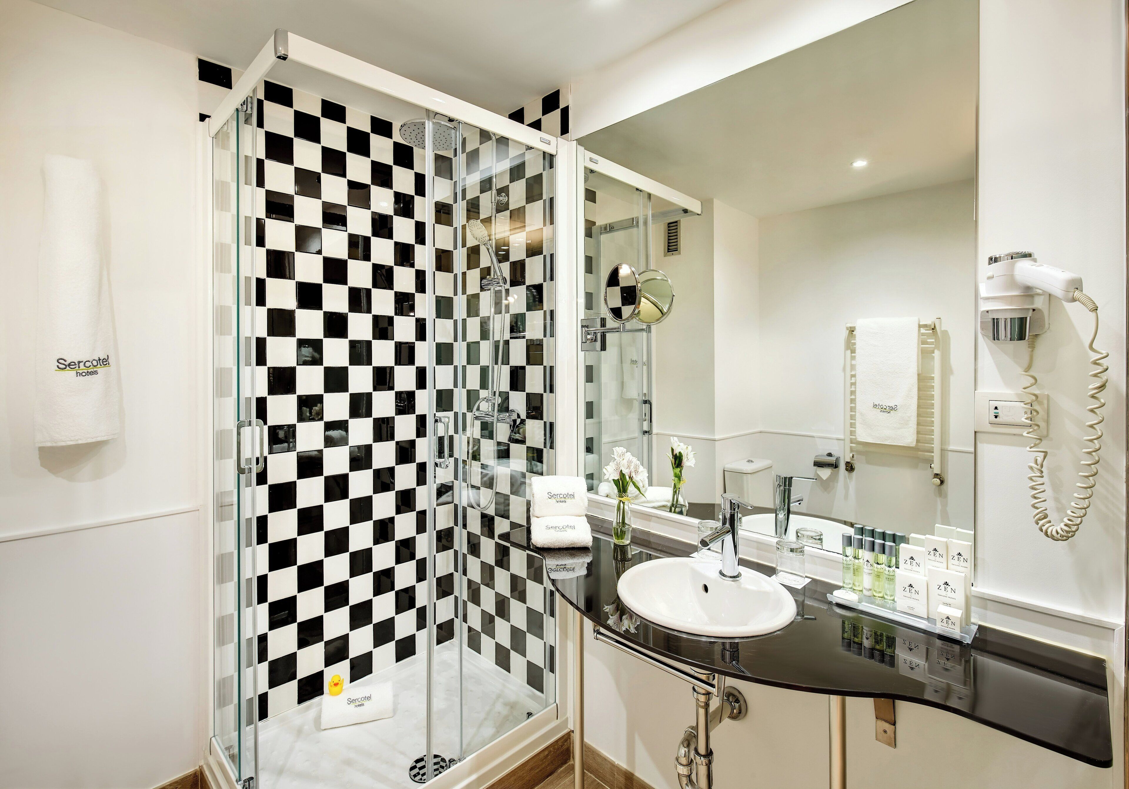 Ein modernes Badezimmer mit einer begehbaren Glasdusche, einem weißen Waschbecken und einem Spiegel.