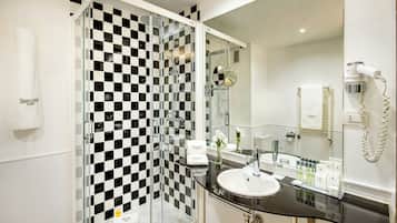 Ein modernes Badezimmer mit einer begehbaren Glasdusche, einem weißen Waschbecken und einem Spiegel.