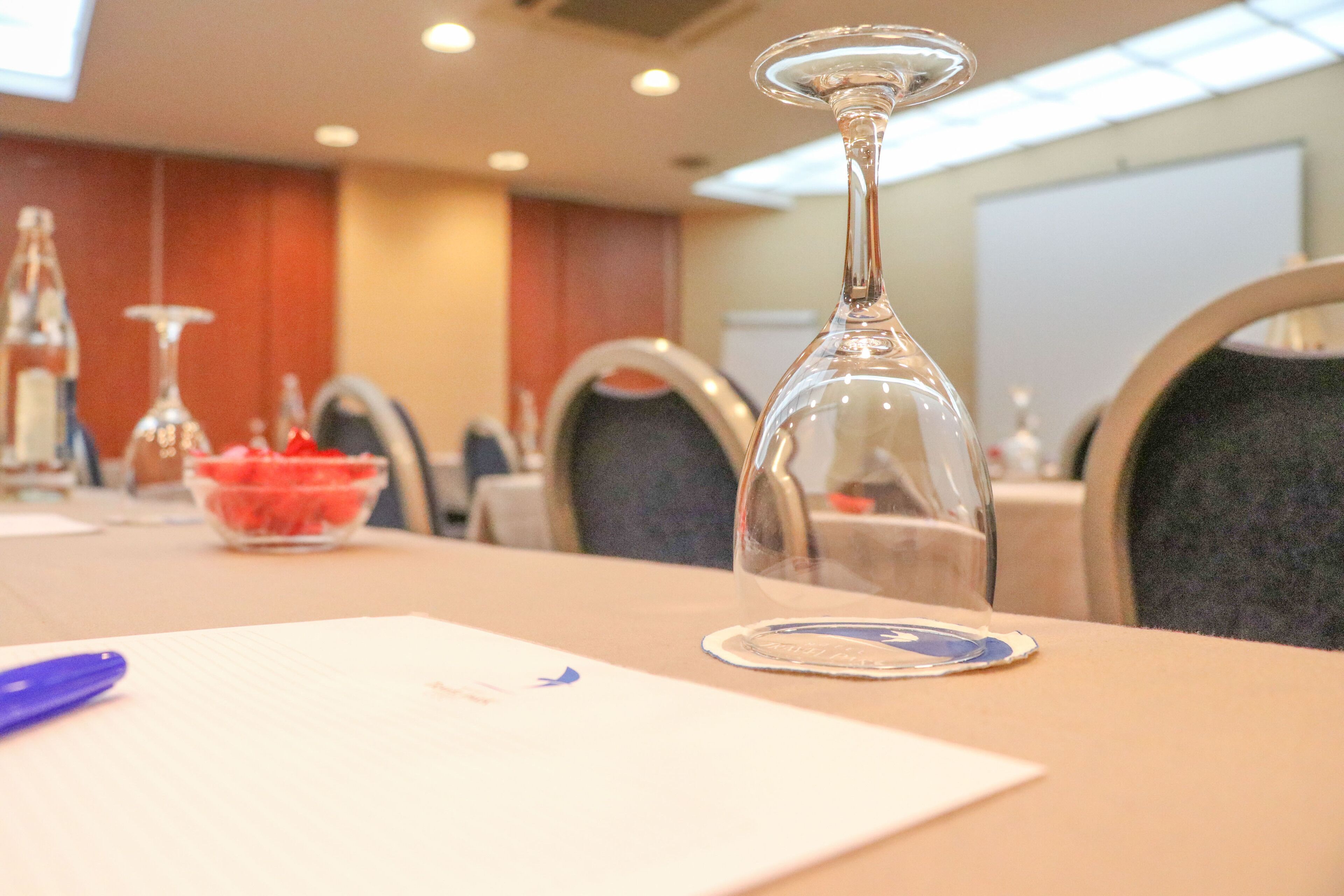 Una mesa de conferencias con una cúpula de cristal como centro, un frutero y un bolígrafo sobre un bloc de notas.