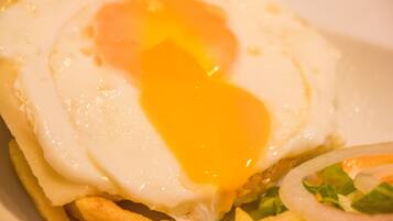 Close-up de um prato de café da manhã com ovo frito, queijo e vegetais.