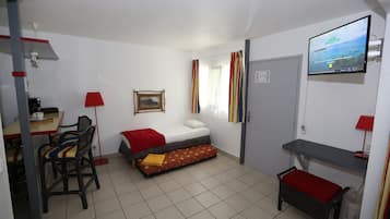 A compact room with a bed, a desk, a chair, a TV, and a window with curtains.