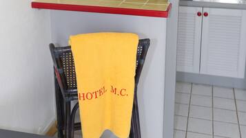 Eine kleine Küche mit roter Arbeitsplatte, einem gelben Handtuch, das an einem Stuhl hängt, und einem Schild mit Rauchverbot.