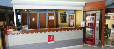 A reception desk with a sign indicating a 3-star rating, a vending machine, and a counter with a basket of flowers.