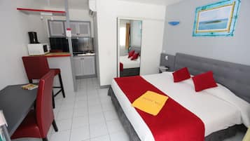 A hotel room with a bed, a desk, and a kitchenette.