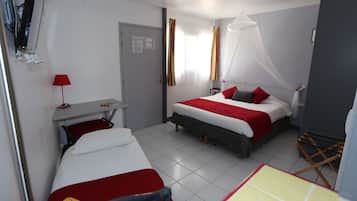Habitación de hotel con cama, escritorio, silla, armario y ventana con cortinas.