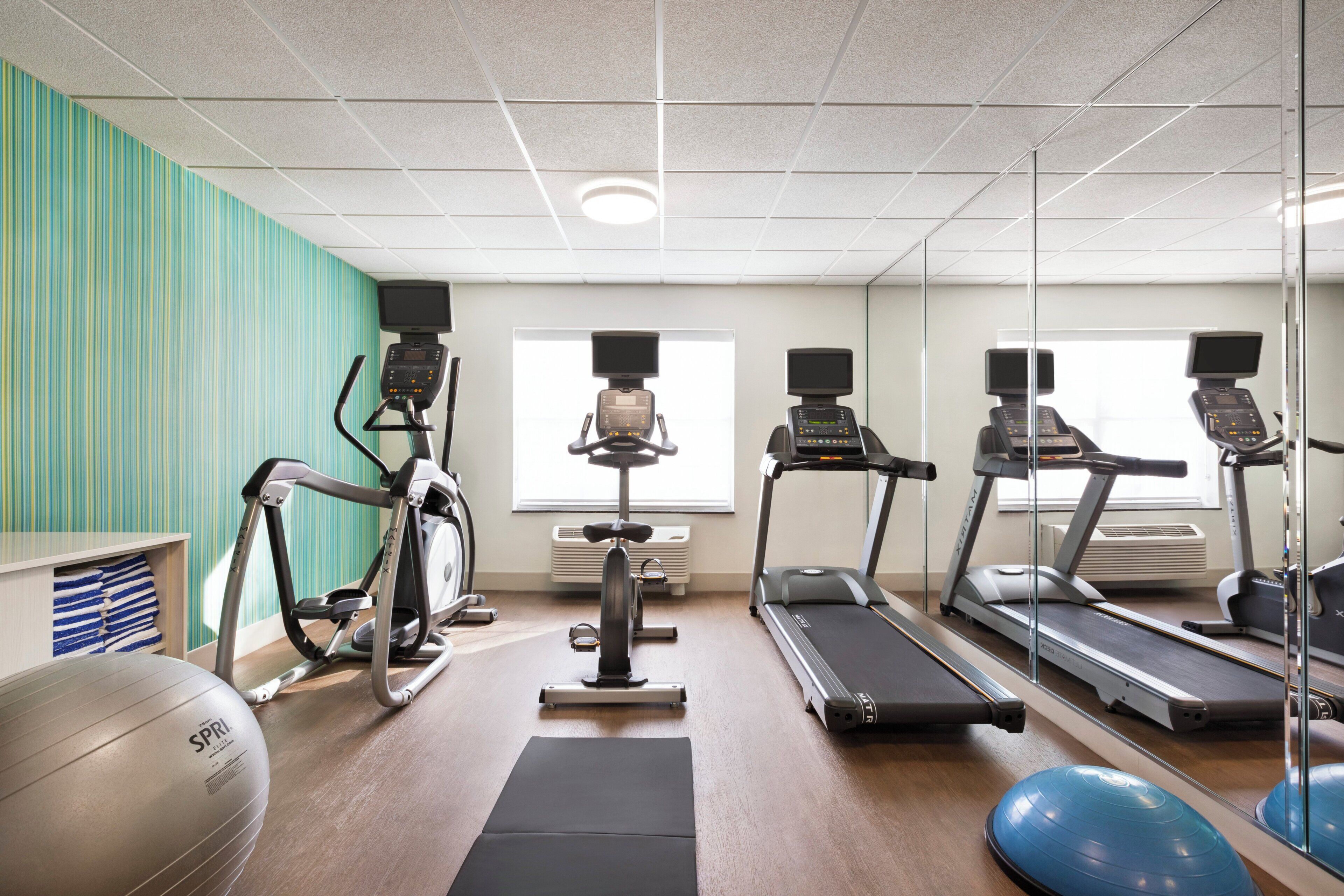 A gym with treadmills, stationary bikes, and exercise balls.