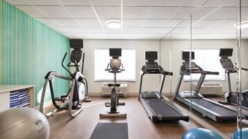 A gym with treadmills, stationary bikes, and exercise balls.