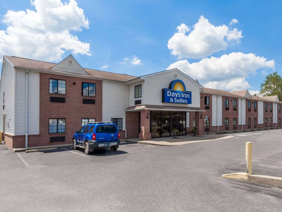 A Days Inn & Suites building with a parking lot and a blue SUV parked in front.