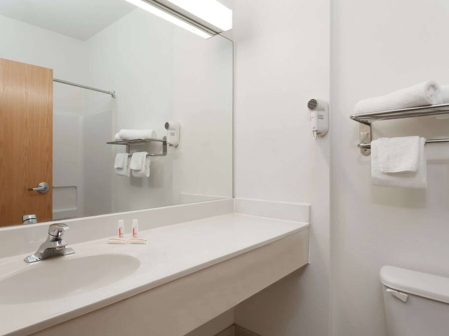 A bathroom with a white sink, a mirror, a towel rack, and a toilet.