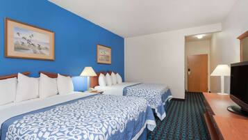 Habitación de hotel con dos camas, televisión, escritorio y alfombra estampada.