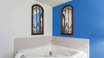 A bathroom with a large bathtub, two wall-mounted mirrors with ornate frames, and a blue accent wall.