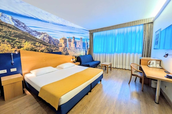 Minibar, escritorio, cortinas blackout y tabla de planchar con plancha