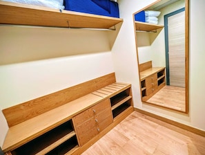 Une chambre avec un lit en bois, une armoire, un miroir et un petit coin salon.