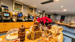 Zona de bufé con diferentes opciones de comida, una estación de café y elementos decorativos como una escultura de madera y poinsettias.