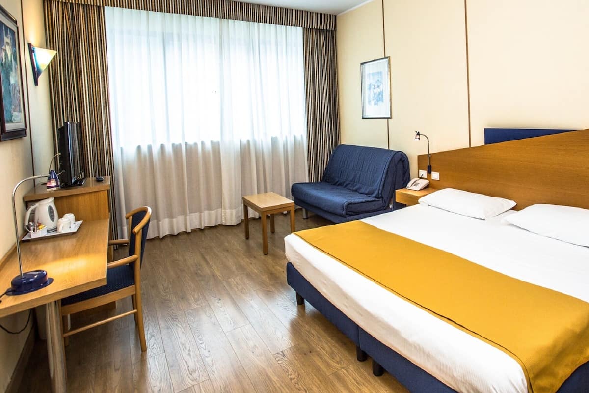 Minibar, escritorio, cortinas blackout y tabla de planchar con plancha