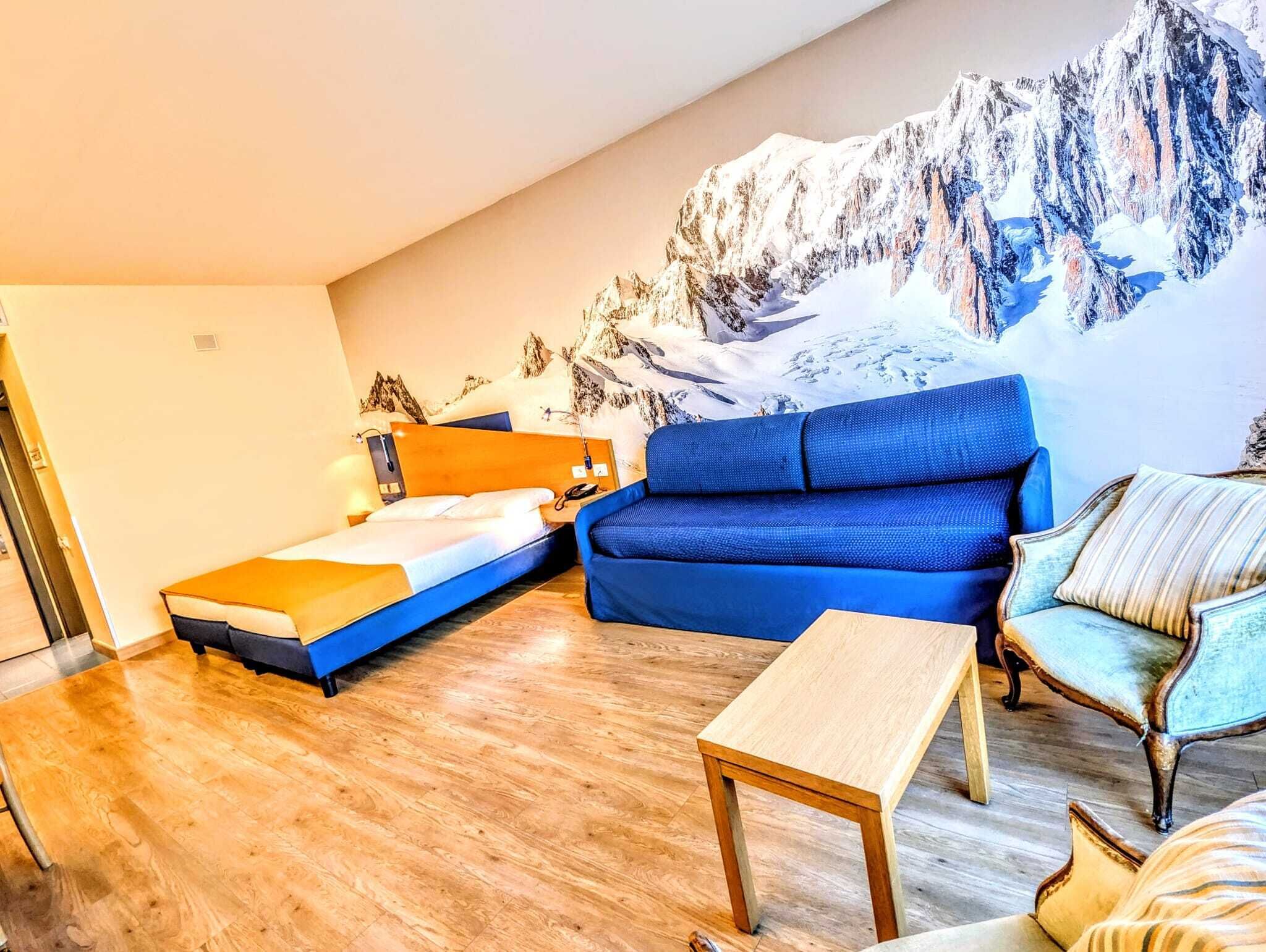 Une chambre avec un lit, un canapé bleu, une table en bois et une chaise.