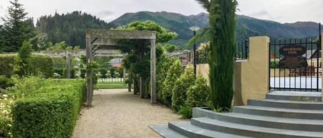 Un camino que lleva a un área de piscina con un pérgola y escalones.