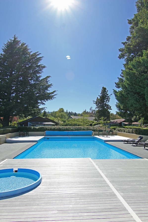 Una piscina al aire libre de temporada, sillones reclinables de piscina