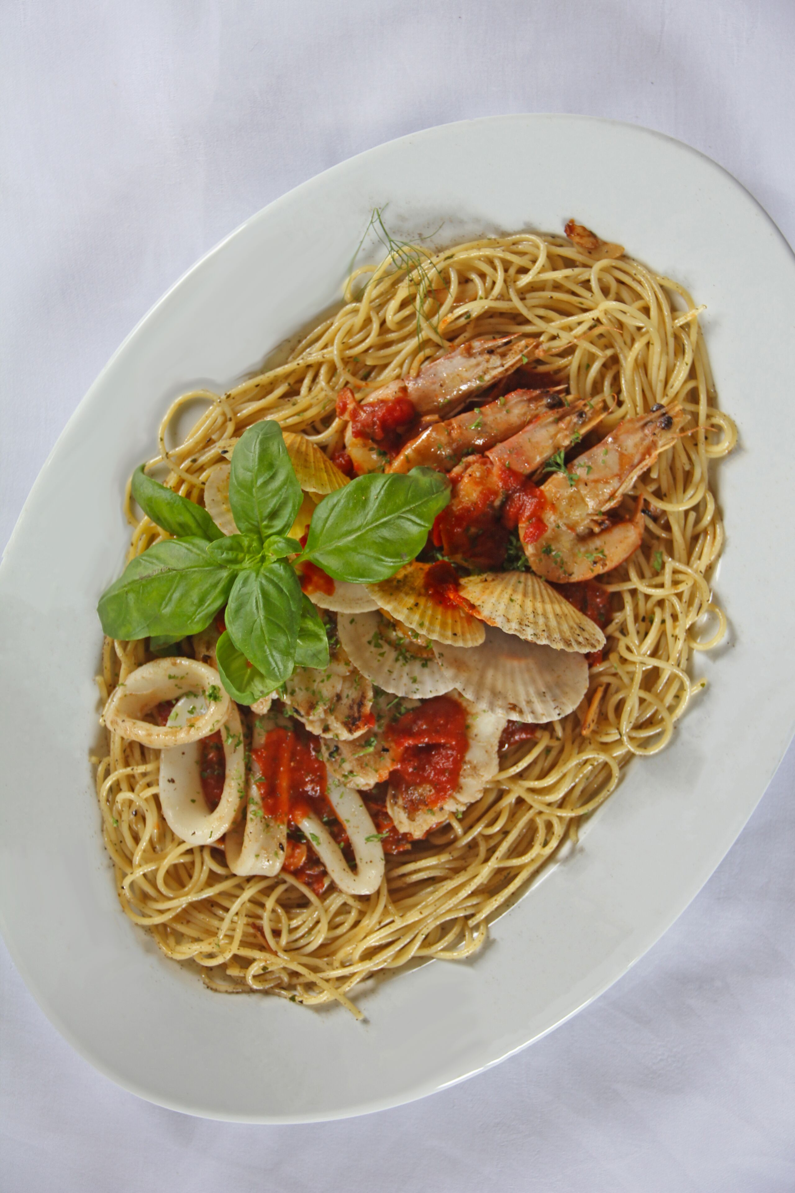 A plate of spaghetti with shrimp, clams, and a basil garnish.