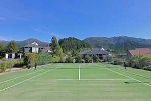 A tennis court with a net in the middle, surrounded by houses and a mountain in the background. - Edit Hanmer Springs (Hanmer Springs)