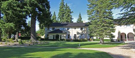 A large building with a symmetrical facade, a central entrance, and a well-maintained lawn.