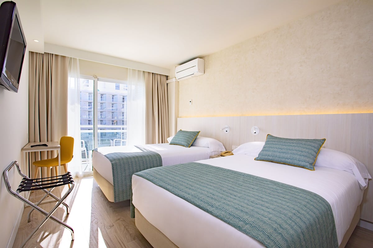 Habitación de hotel con dos camas, televisión, escritorio y una silla.