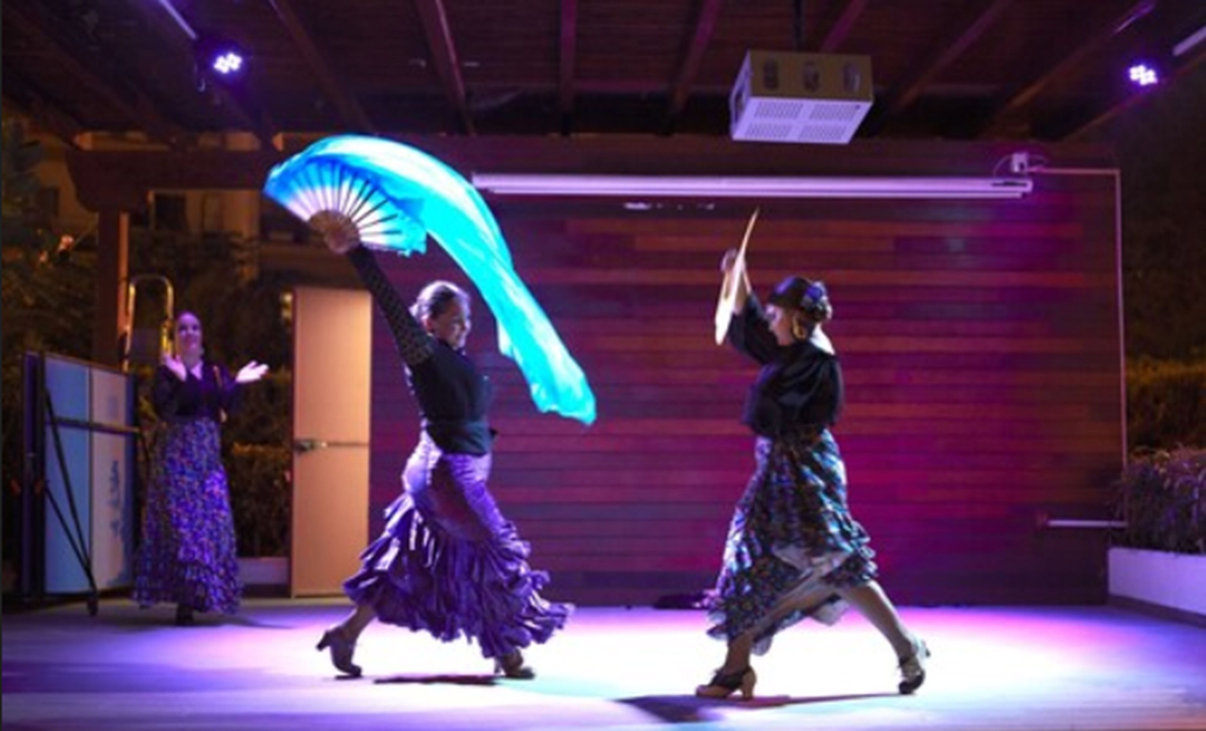 A stage with three dancers in traditional attire performing.