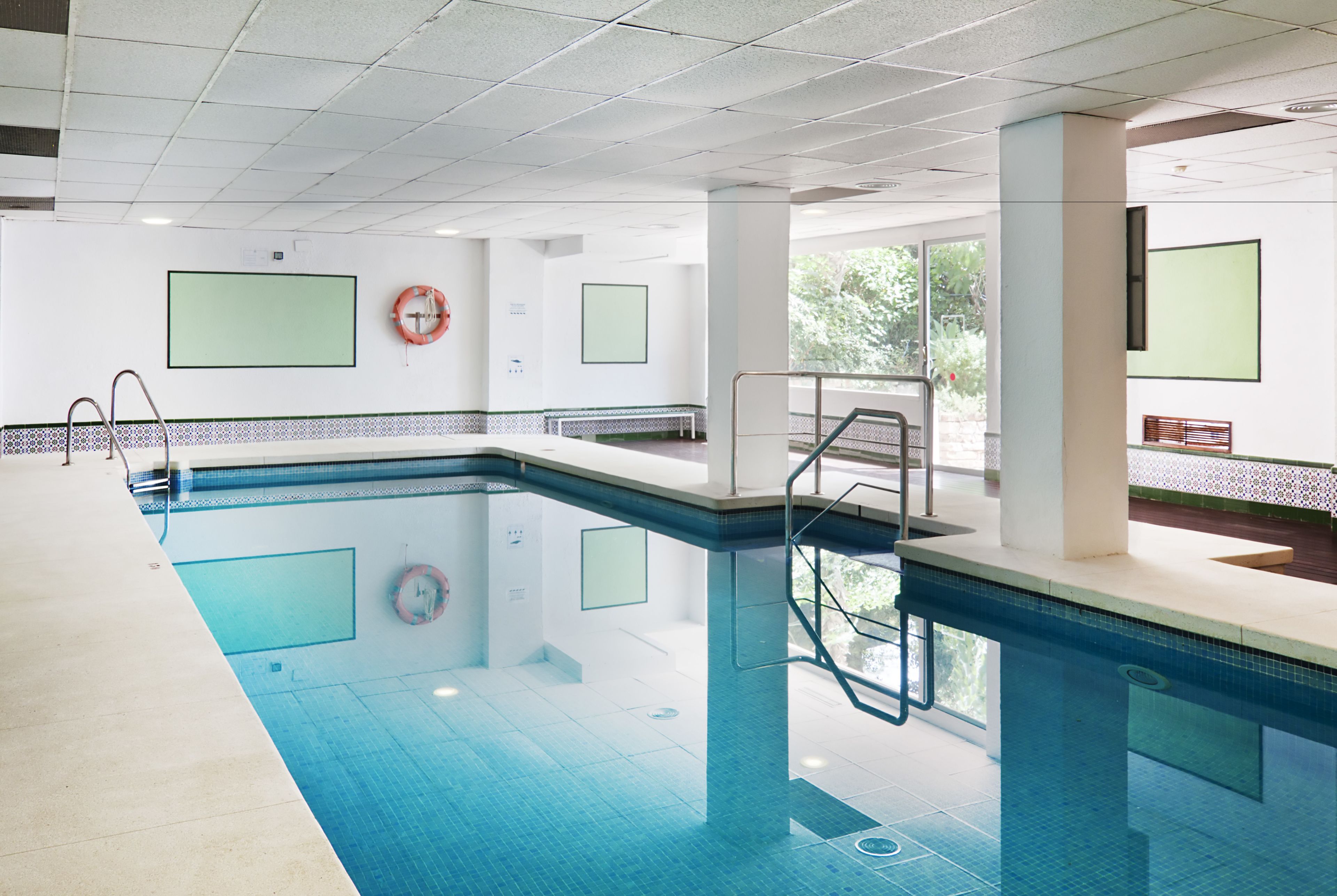 Una piscina interior amb aigua cristal·lina, un flotador i una cadira.