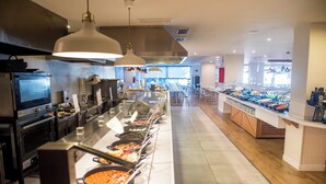 A buffet area with multiple food stations, a kitchen area with ovens and a stove, and a seating area with tables and chairs. - Hotel Palmasol Puerto Marina (Benalmádena)