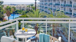 A balcony with a table, chairs, and a view of a pool and buildings. - Hotel Palmasol Puerto Marina (Benalmádena)