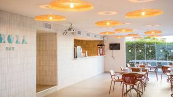 Zona de bar con pared de azulejos, mostrador y varias lámparas colgantes naranjas.