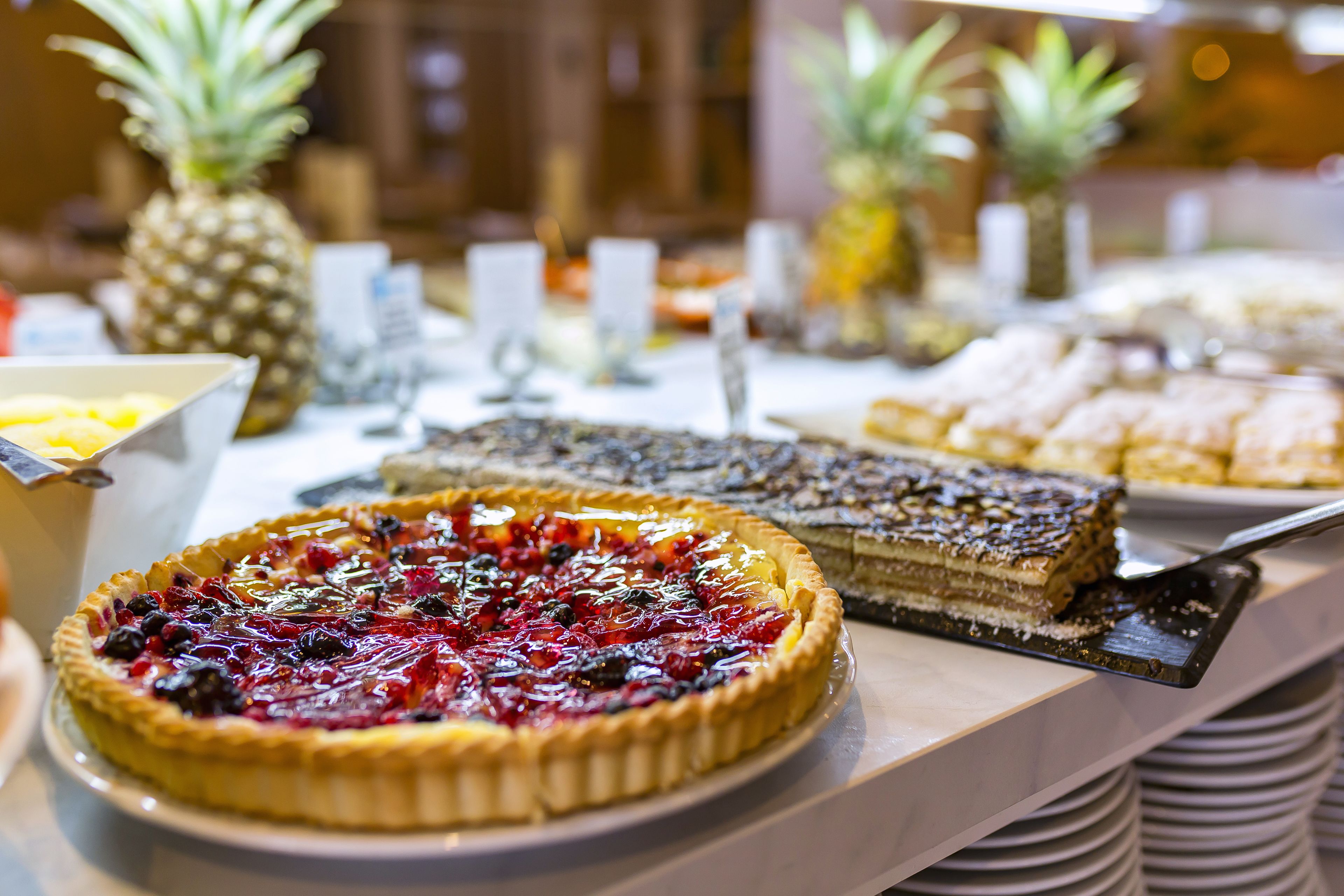 Un bufé con diversos pasteles y postres, incluyendo una tarta de cerezas y un pastel de varias capas.