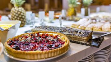 Un bufé con diversos pasteles y postres, incluyendo una tarta de cerezas y un pastel de varias capas.