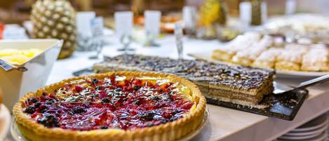 A buffet with various pies and desserts, including a cherry pie and a layered cake.