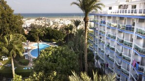 A hotel with a pool, palm trees, and a view of the ocean. - Hotel Palmasol Puerto Marina (Benalmádena)