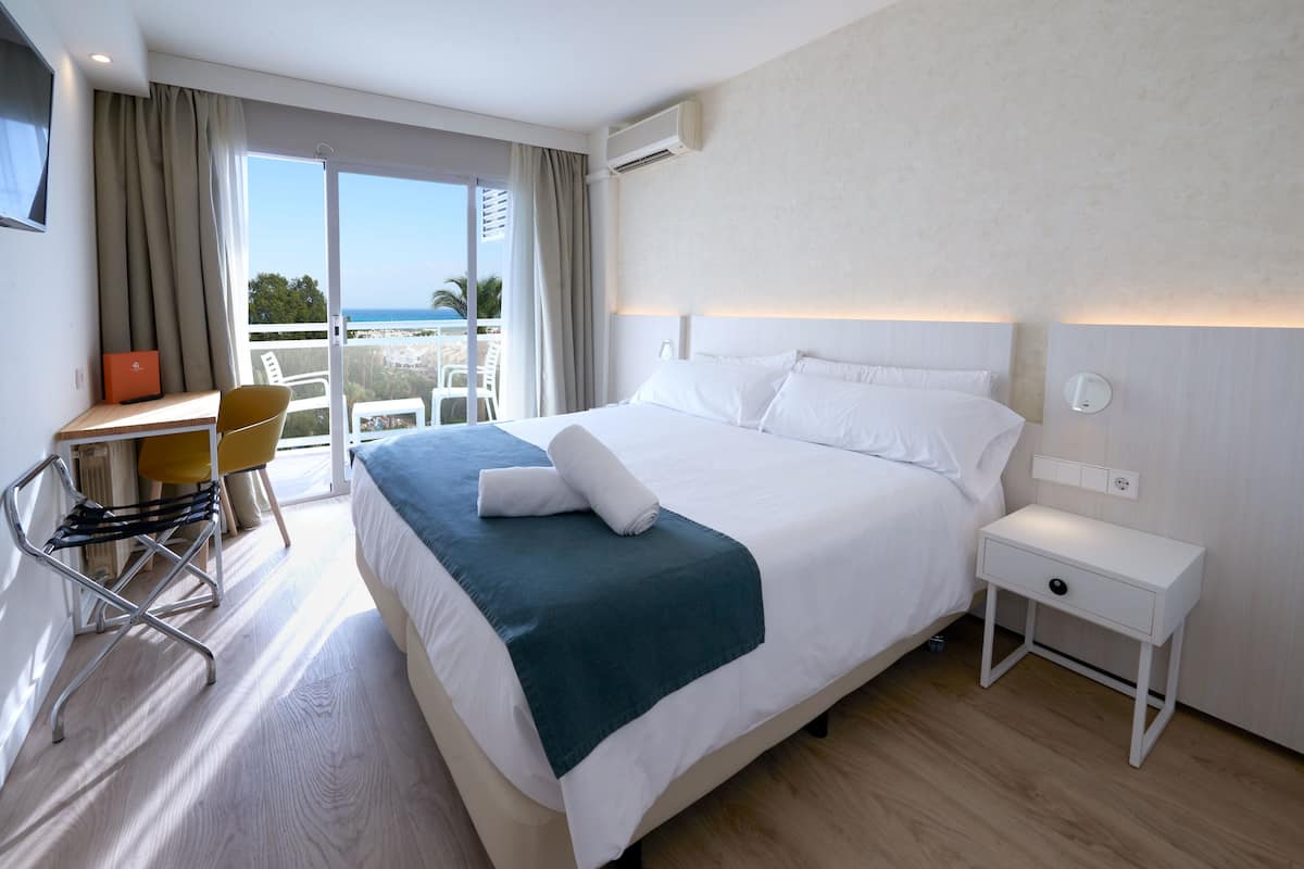 Una habitación de hotel con cama, escritorio, silla y vista al océano.