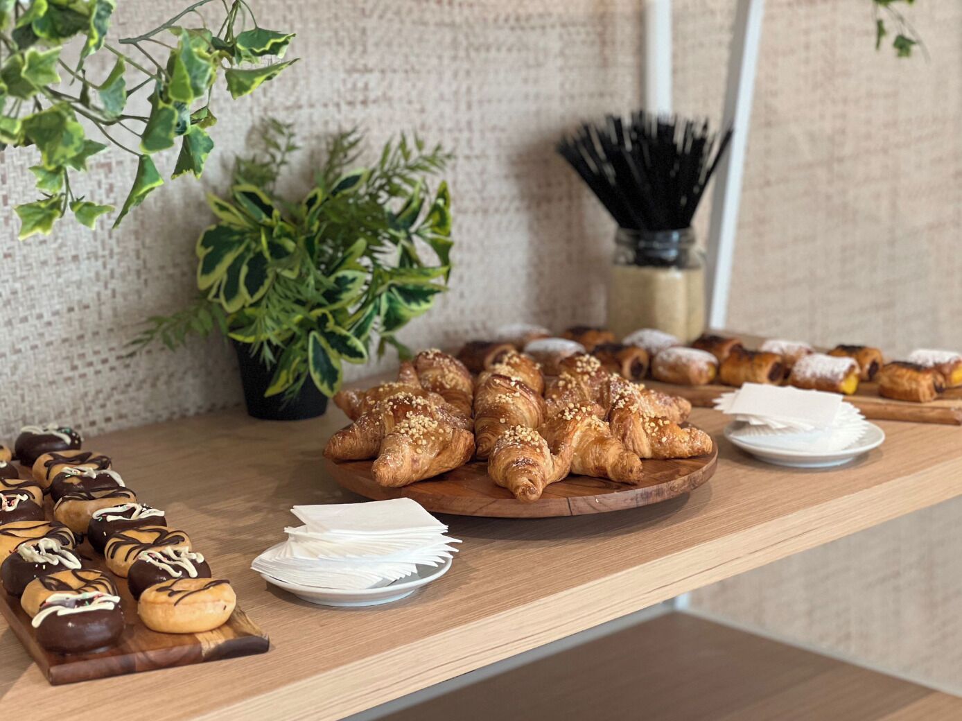 A wooden table with pastries and a potted plant.