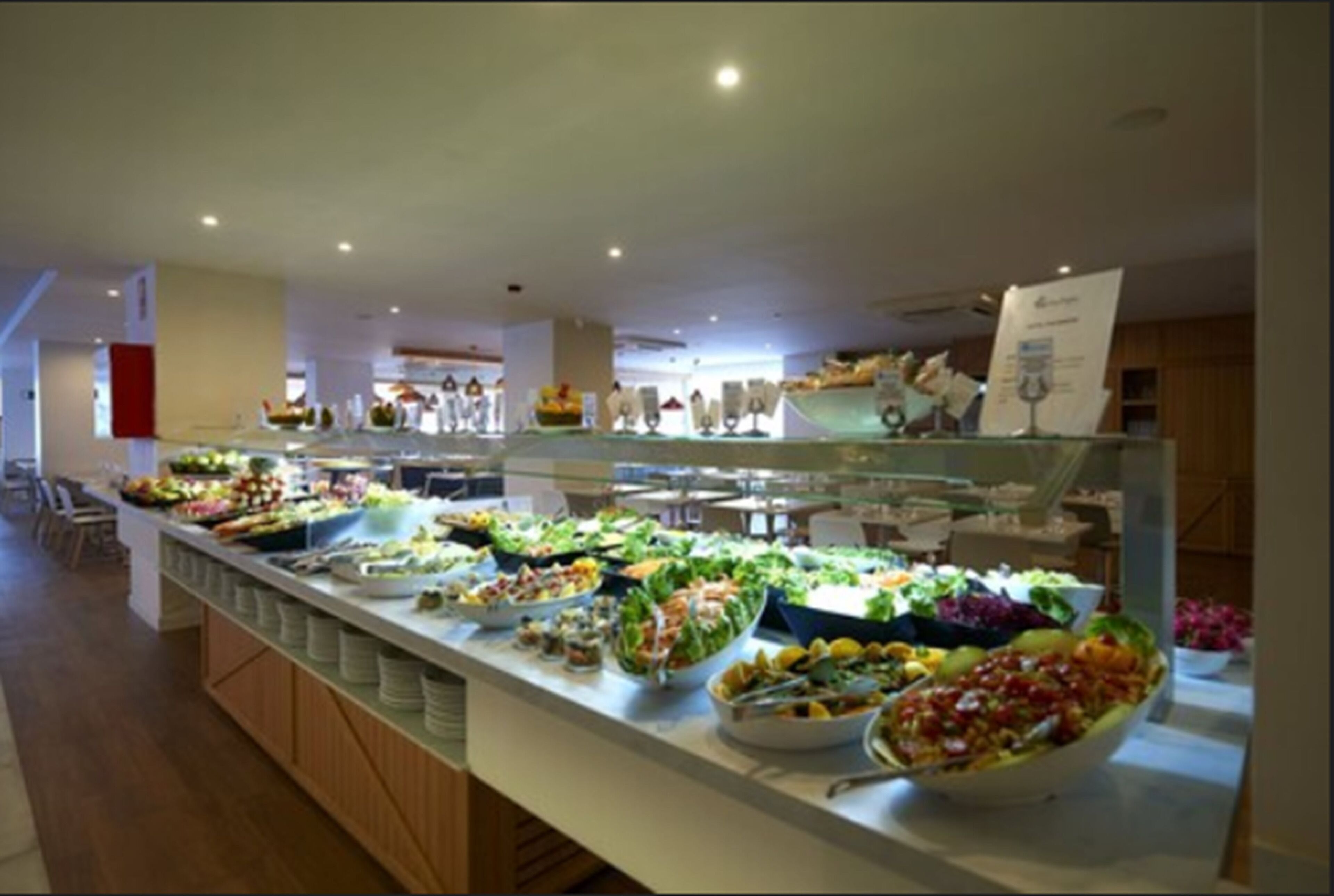 Un buffet con diverse opzioni tra cui insalate, frutta e altri piatti.
