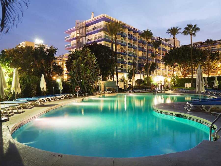 Una piscina techada, una piscina al aire libre, sombrillas